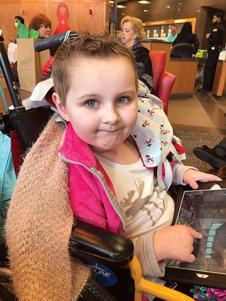 Between and during tests and treatments, Sawyer has fun with her “cancer warrior” friends and plays on her tablet.